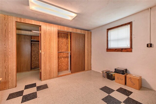 unfurnished bedroom with wood walls, a closet, and light tile patterned floors