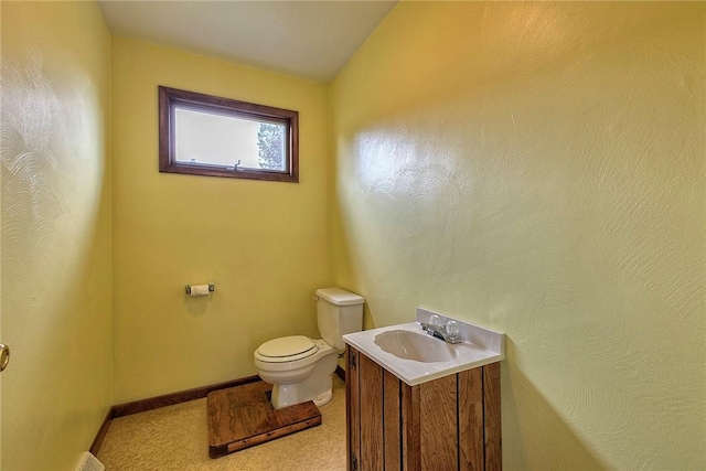 half bath with toilet, baseboards, vaulted ceiling, and vanity