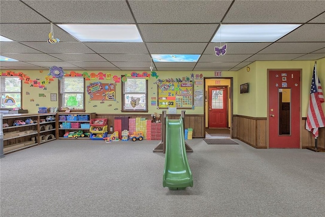 recreation room with a paneled ceiling, carpet floors, and wainscoting