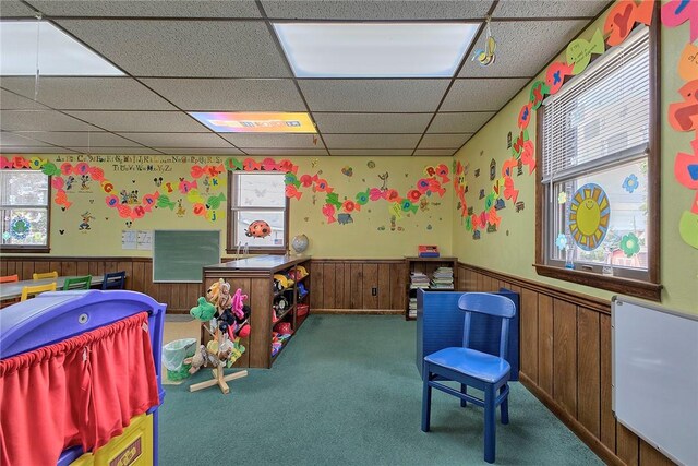 rec room with a drop ceiling and dark carpet