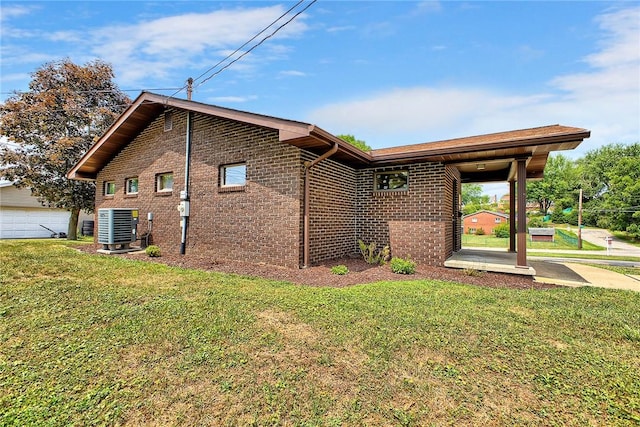 rear view of house with a garage, a yard, brick siding, and cooling unit