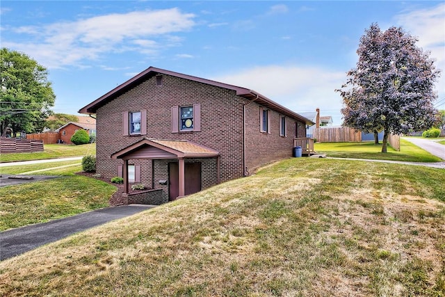 view of side of home with fence, a lawn, and brick siding