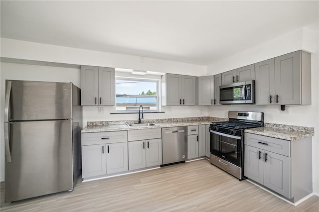 kitchen with sink, stainless steel appliances, and light hardwood / wood-style floors