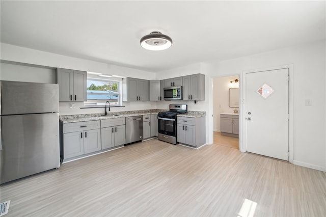 kitchen featuring gray cabinets, stainless steel appliances, light hardwood / wood-style floors, and sink