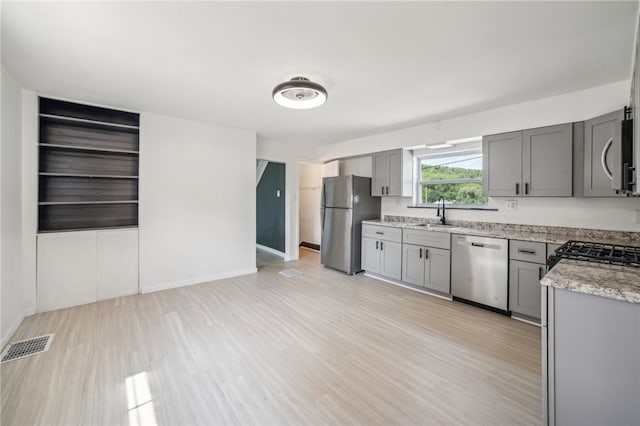 kitchen featuring sink, appliances with stainless steel finishes, light hardwood / wood-style flooring, and gray cabinetry