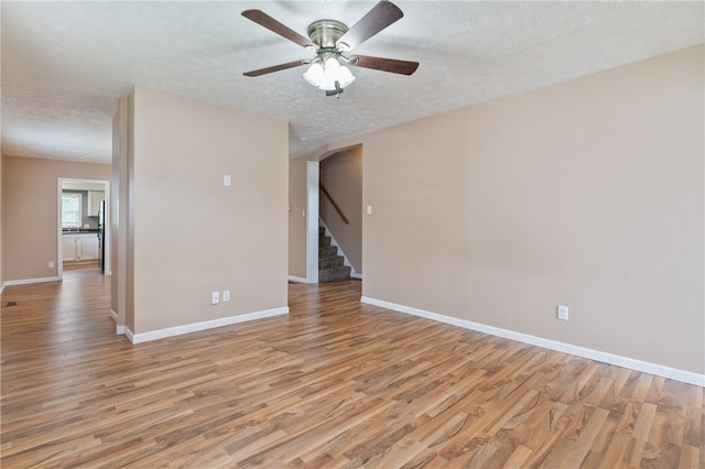 empty room with light hardwood / wood-style floors, a textured ceiling, and ceiling fan