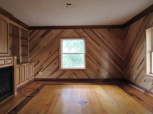 unfurnished living room with wooden walls and light hardwood / wood-style floors