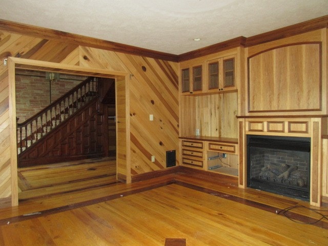 unfurnished living room featuring wooden walls and light hardwood / wood-style flooring