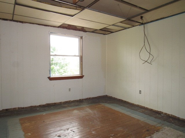 unfurnished room featuring wood-type flooring and a drop ceiling