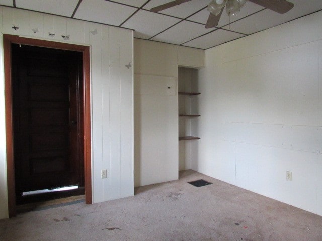 carpeted spare room featuring a paneled ceiling and ceiling fan