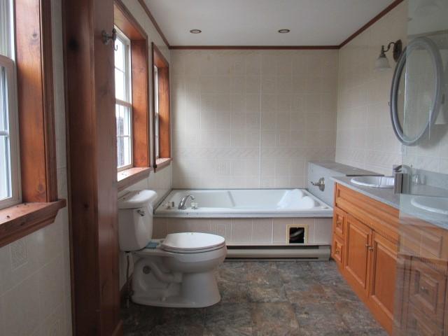 bathroom featuring vanity, tile walls, and tiled bath