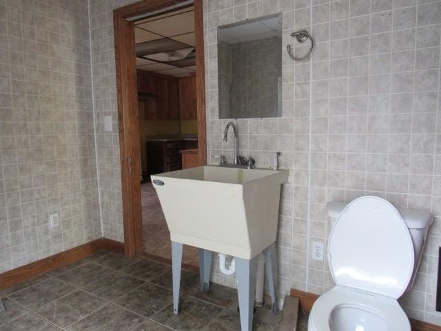 bathroom featuring tile patterned flooring, sink, tile walls, and toilet