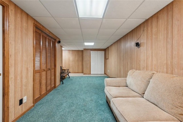 living area with carpet flooring, a paneled ceiling, and wood walls