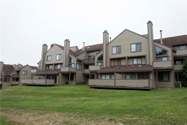 back of house with central AC unit and a lawn