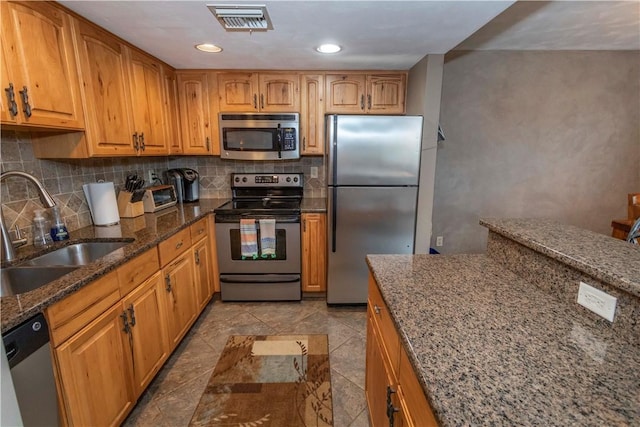 kitchen with sink, dark stone counters, decorative backsplash, light tile patterned flooring, and appliances with stainless steel finishes