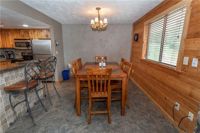 dining room with wood walls and a chandelier