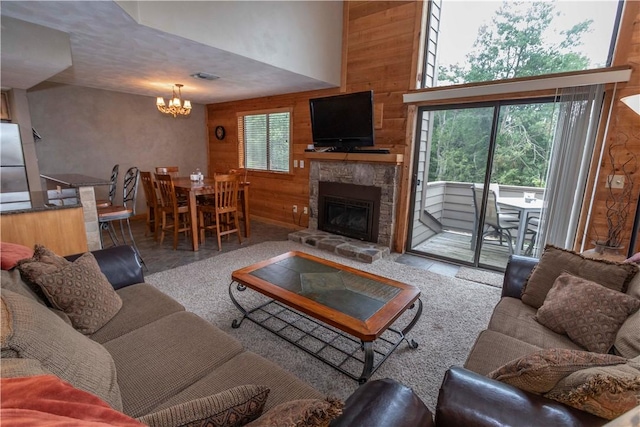 living room with a stone fireplace, wooden walls, plenty of natural light, and a high ceiling