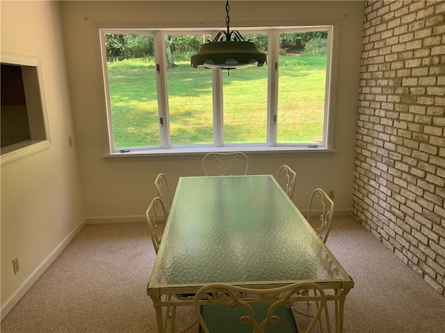 carpeted dining space featuring brick wall