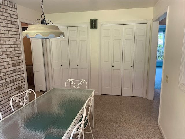 unfurnished dining area featuring carpet and brick wall