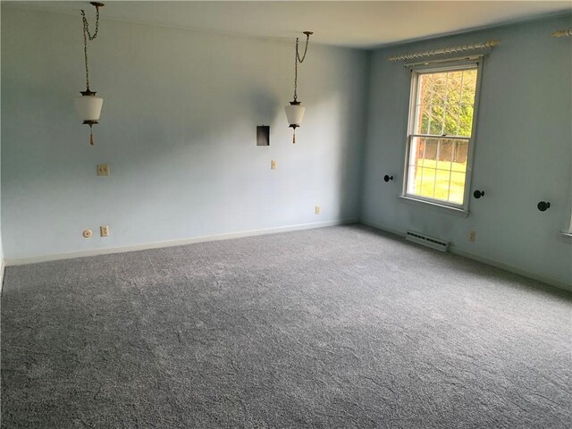 carpeted empty room featuring a baseboard heating unit