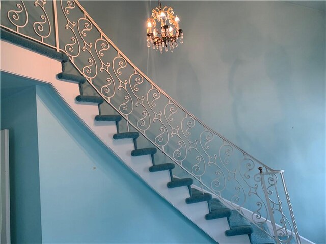 stairway with a notable chandelier and a towering ceiling