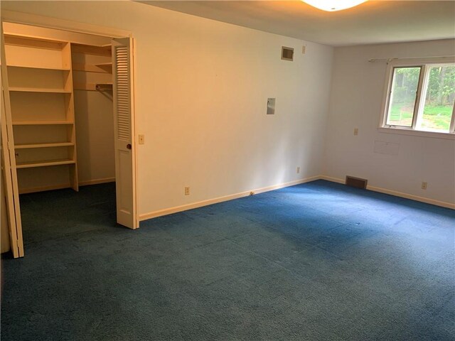 unfurnished bedroom with dark colored carpet and a closet