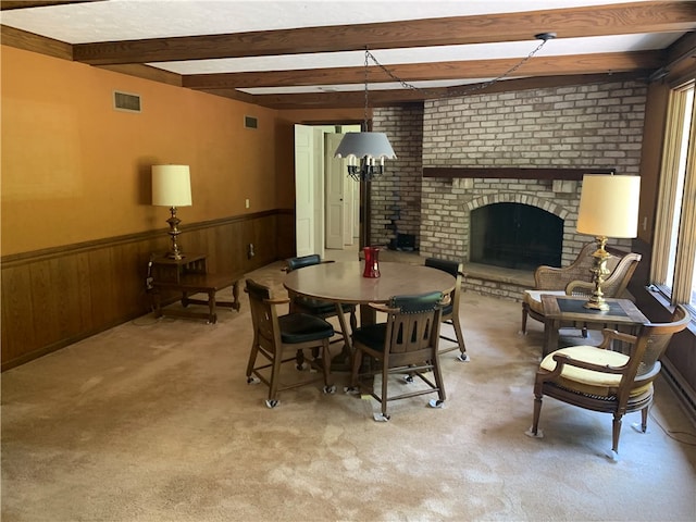 dining room featuring light carpet, a fireplace, and beam ceiling