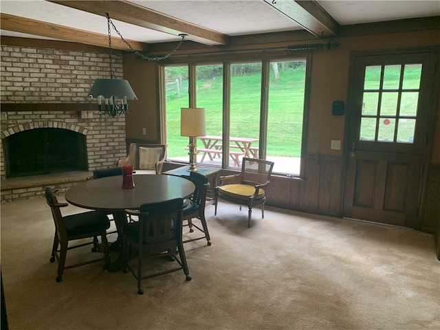 carpeted dining area with beamed ceiling and a fireplace