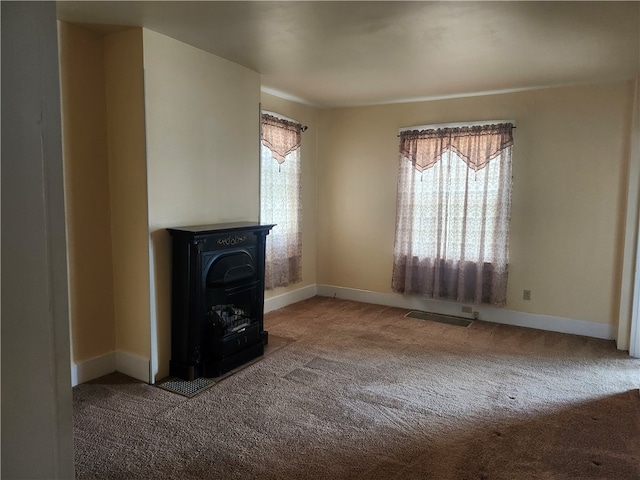 unfurnished living room with a wood stove and carpet