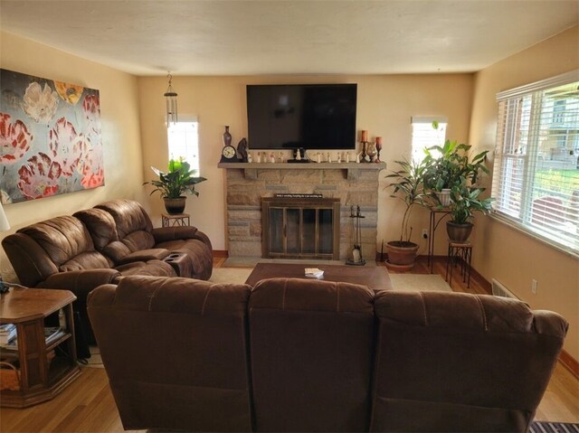 living room featuring a stone fireplace and light wood-type flooring