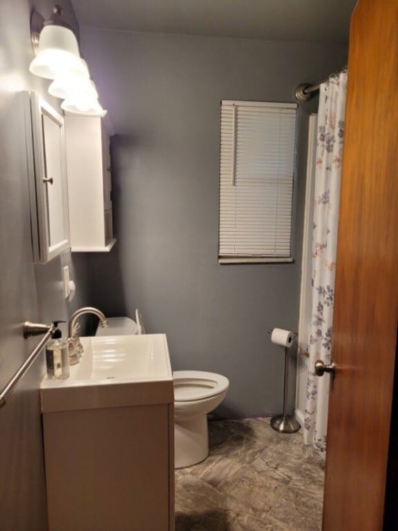 full bathroom featuring a shower with curtain, vanity, and toilet