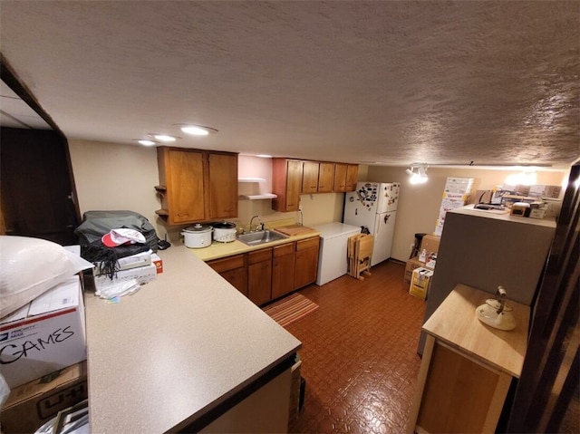 kitchen featuring a textured ceiling, sink, and white refrigerator