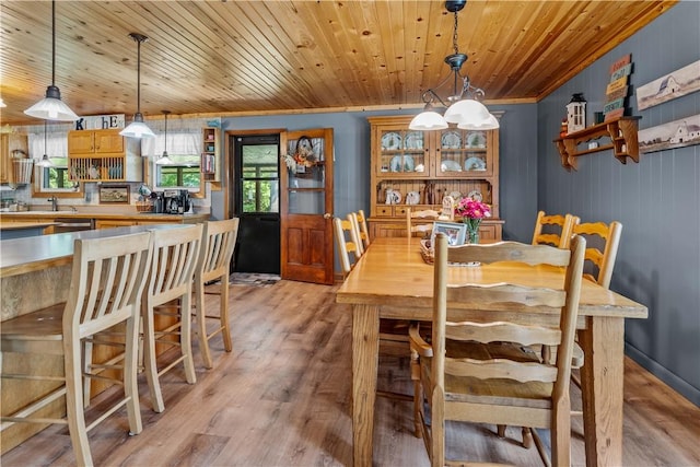 dining space with ornamental molding, light hardwood / wood-style flooring, wooden walls, and wooden ceiling