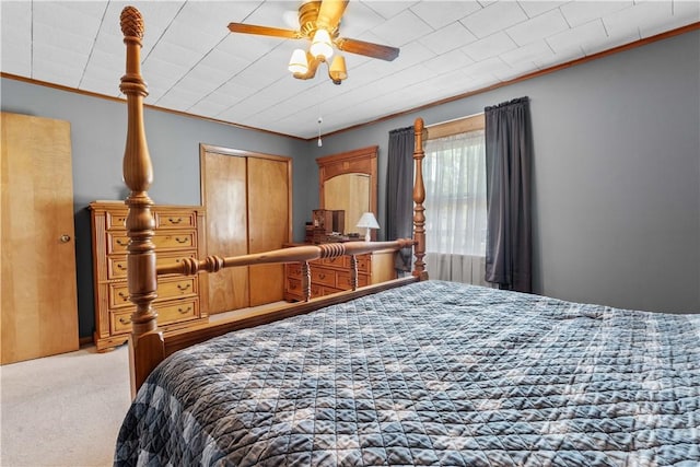 carpeted bedroom with a closet, ceiling fan, and ornamental molding