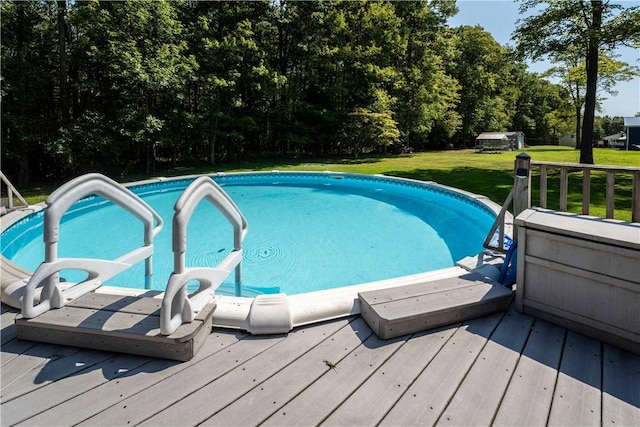 view of pool with a lawn and a wooden deck