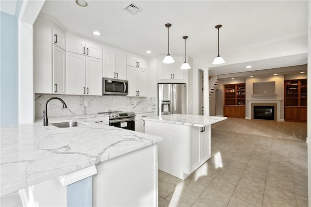 kitchen featuring white cabinetry, stainless steel appliances, decorative light fixtures, and a center island