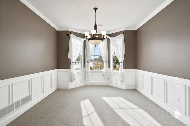 carpeted spare room featuring ornamental molding and an inviting chandelier