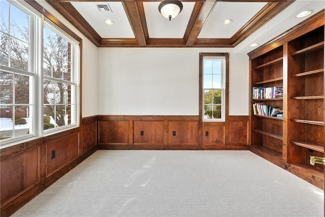 spare room with ornamental molding, coffered ceiling, light carpet, beam ceiling, and built in shelves