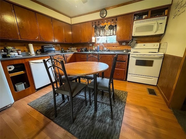 kitchen featuring white appliances, sink, light hardwood / wood-style flooring, and wood walls