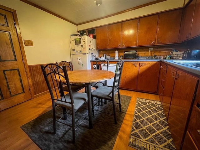 kitchen featuring hardwood / wood-style flooring, ornamental molding, wooden walls, and white appliances