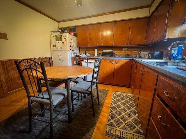 kitchen featuring sink, white refrigerator, ornamental molding, wooden walls, and dark hardwood / wood-style floors