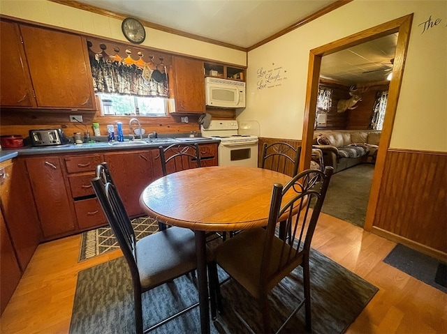 dining space featuring sink, ornamental molding, and light hardwood / wood-style floors