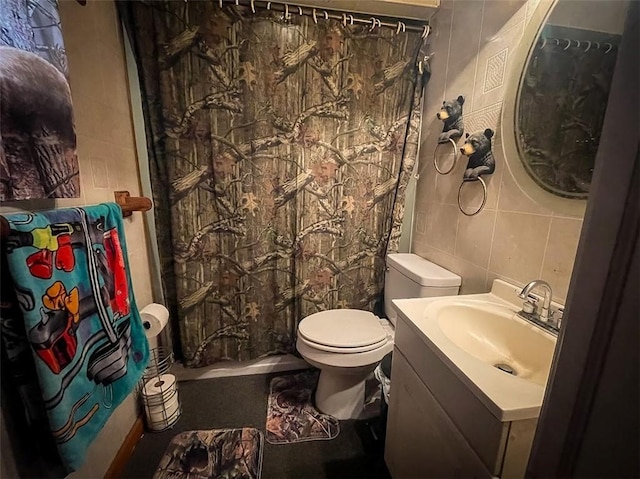 bathroom featuring vanity, tile walls, and toilet