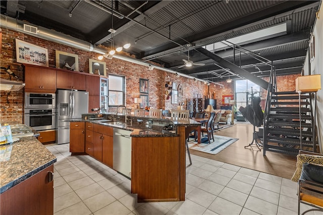 kitchen with stainless steel appliances, sink, brick wall, and a wealth of natural light