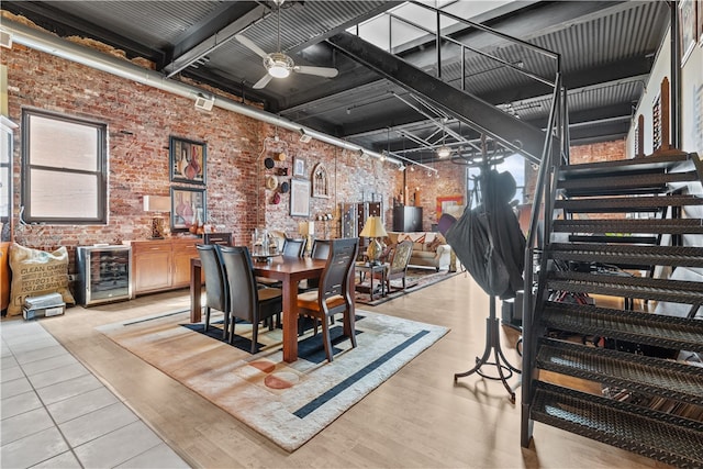 dining room with wine cooler, light hardwood / wood-style flooring, brick wall, and ceiling fan