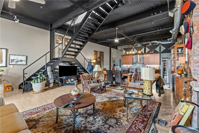 living room with hardwood / wood-style flooring, brick wall, and ceiling fan