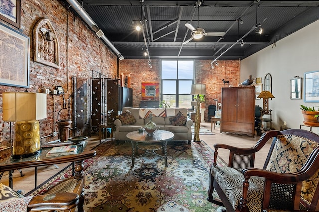 living room featuring brick wall, ceiling fan, rail lighting, and a towering ceiling