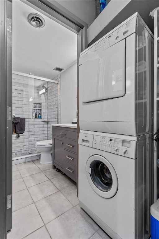 laundry room featuring stacked washer and clothes dryer and light tile patterned floors