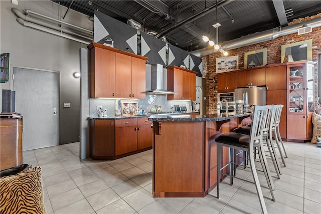 kitchen with brick wall, a towering ceiling, an island with sink, and stainless steel appliances