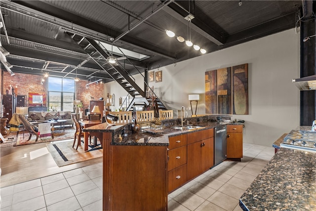 kitchen featuring stainless steel dishwasher, sink, dark stone counters, and light tile patterned floors